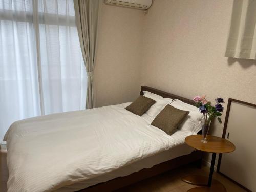 sypialnia z białym łóżkiem i wazą kwiatów w obiekcie 日式庭院豪宅 