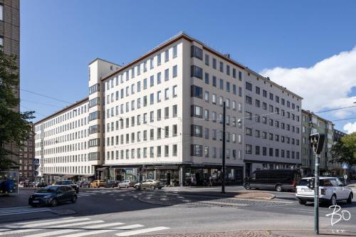 un grande edificio bianco su una strada di città con le auto di Scandic Primo Apartments - Malminkatu 49m2 a Helsinki