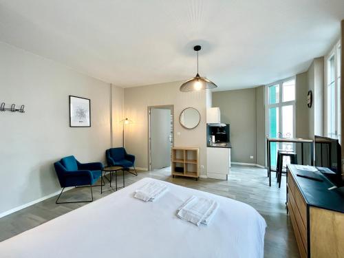 - une chambre avec un grand lit blanc et des chaises bleues dans l'établissement Suite Orphelins 3 1er, à Reims