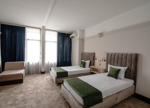 um quarto de hotel com duas camas e uma cadeira em Garni Hotel Jugoslavija em Belgrado