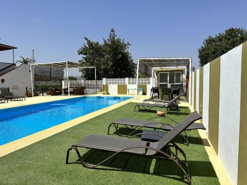 a swimming pool with lounge chairs next to a house at Casa Rural Humberto con 3 dormitorios in Málaga
