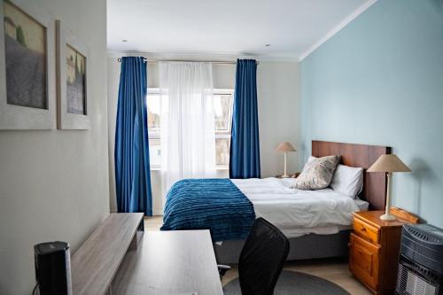 a bedroom with a bed and a window with blue curtains at 3 on Tessa Guesthouse in Johannesburg