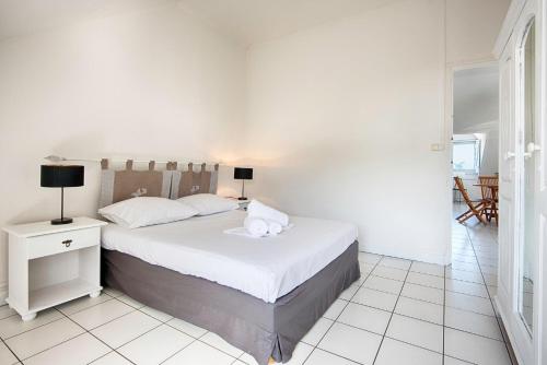 a white bedroom with a bed with two pillows on it at Le Bulbul - T2 à 100m de la plage - La Saline les Bains in La Saline les Bains