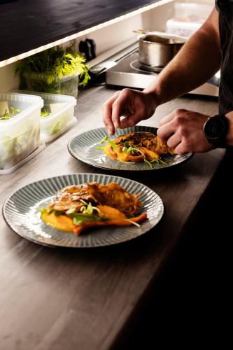 a person holding two plates of food on a counter at The Falcon Hotel in Allinge