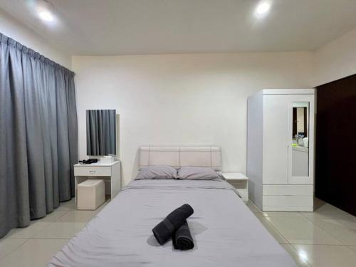 ein Schlafzimmer mit einem großen Bett mit einem schwarzen Objekt darauf in der Unterkunft Comfy Suite with Netflix At Setia Alam in Shah Alam