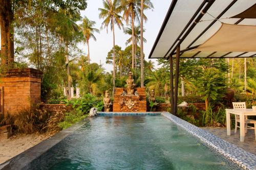 una piscina en un jardín con una fuente en The White Knot Koh Chang, en Ko Chang