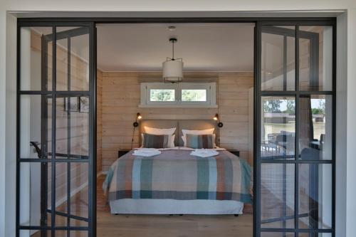a bedroom with a bed and sliding glass doors at Frei wie der Wind-Chalets in Dierhagen
