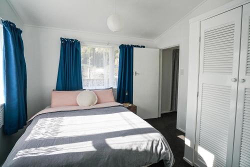 - une chambre avec des rideaux bleus et un grand lit dans l'établissement The Hidden Gem - tranquility close to town, à Wellington