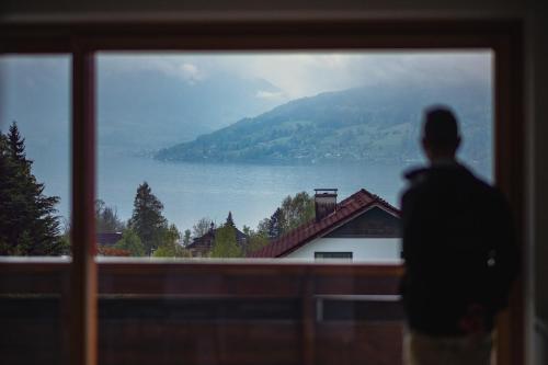 a man looking out of a window at a lake at Kaisigen43 in Steinbach am Attersee