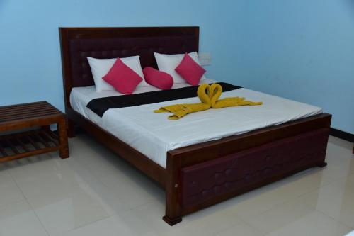 a bedroom with a bed with pink and yellow pillows at The New Crown Hotel in Dambulla