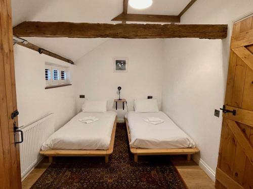2 camas individuales en una habitación con puerta en Stable Cottage at Lee Wick Farm Cottages & Glamping en Clacton-on-Sea