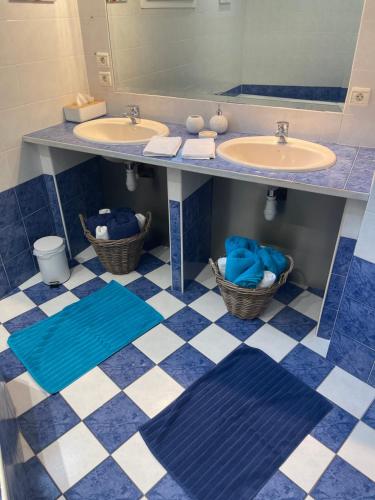 La salle de bains est pourvue de 2 lavabos ainsi que de sols en damier bleu et blanc. dans l'établissement Au Jardin de Papy, à Véranne