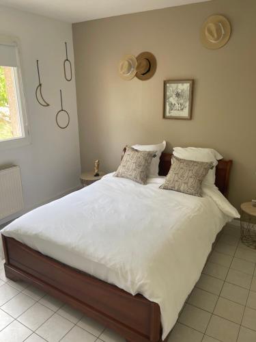 ein Schlafzimmer mit einem großen Bett mit weißer Bettwäsche und Kissen in der Unterkunft Au Jardin de Papy in Véranne