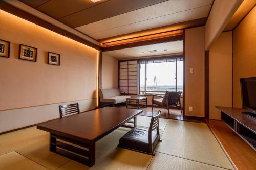 a living room with a table and chairs and a television at Tokachigawa Onsen Daiichi Hotel in Otofuke