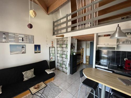 un salon avec un canapé noir et une table dans l'établissement Le cocon du rivage, à Mimizan