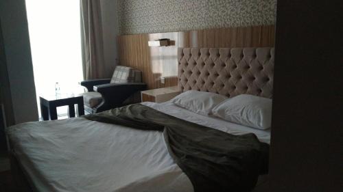 a bedroom with a bed with a headboard and a window at Grand Mardin Hotel in Mersin