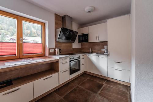 a kitchen with white cabinets and a window at Gästehaus Fohringer in Kelchsau