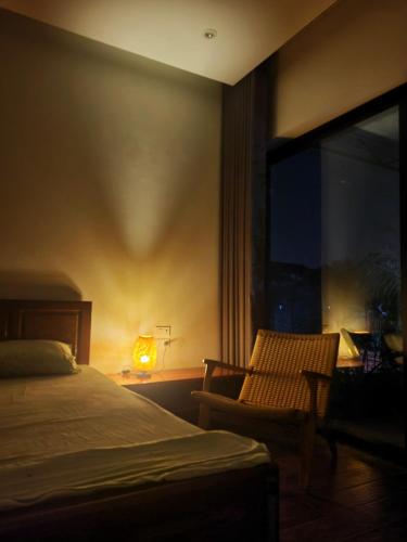 a bedroom with a bed and a chair and a window at Noi Bai Flight Path Homestay in Hanoi