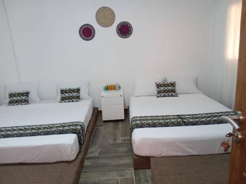 twee bedden in een kamer met witte muren bij Warang - Nianing Chambres,Salle de séminaires et réunion in Darou Rhamane