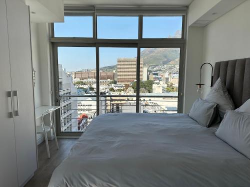 a bedroom with a large bed and a large window at Studio corner unit in the heart of CBD in Cape Town