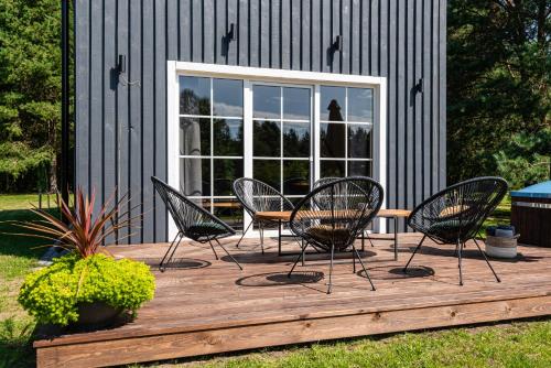four chairs and a table on a wooden deck at Sodyba pas Brolius - Mažasis Namelis - Entire Barn House 85m2 in Priekulė