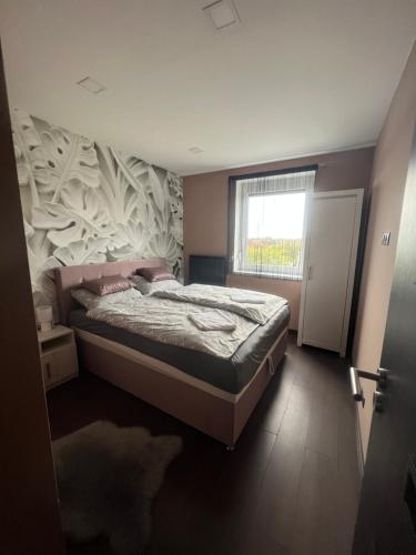 1 dormitorio con cama, ventana y puerta en Green Penthouse, en Tiszaújváros