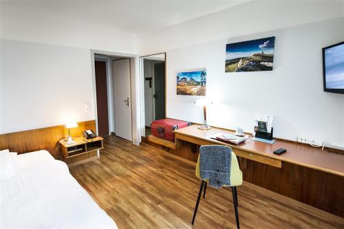 a hotel room with a desk and a bed and a bed and a chair at City Hotel Biel Bienne Free Parking in Biel