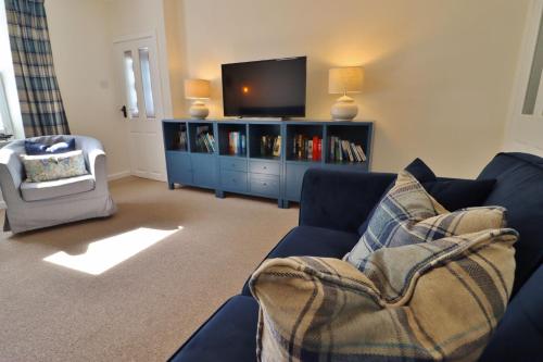 a living room with a blue couch and a tv at 14 Union Street in Kirkcudbright