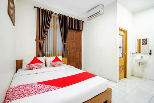 1 dormitorio con 1 cama con almohadas rojas y blancas en Super OYO 250 De'gadri Ndalem en Yogyakarta