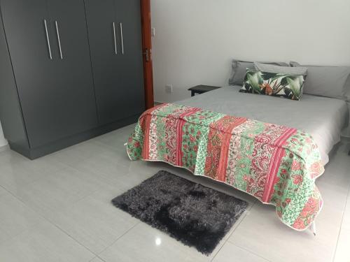 a bedroom with a bed with a blanket and a rug at Lotus Accommodation in Kingsburgh