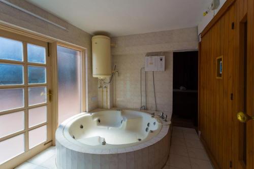 baño con una gran bañera blanca y ventana en Toshali Royal View ,S H I M L A, en Kūfrī