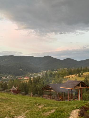 a cabin in a field with mountains in the background at Мелодія Гір .Апартаменти з видом на гори . in Vorokhta