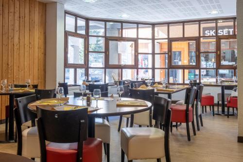 a restaurant with tables and chairs and windows at VVF Val-Cenis Haute-Maurienne in Lanslevillard