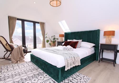 a bedroom with a large bed with a green headboard at Green Cottage Luxury Stay Peak District near Alton Towers in Stanton