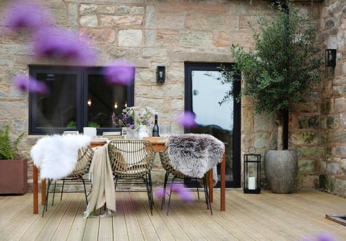 uma mesa e cadeiras num quarto com uma parede de pedra em Green Cottage Luxury Stay Peak District near Alton Towers em Stanton