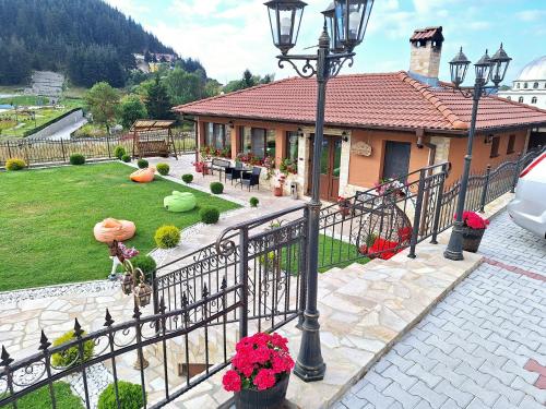 una casa con una valla y un patio con flores en Perla en Dospat