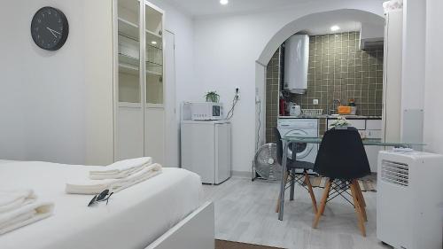Dieses weiße Zimmer verfügt über einen Tisch und eine Küche. in der Unterkunft STUDIO MADALENA in Lissabon