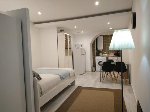 ein Schlafzimmer mit einem Bett und einem Tisch sowie eine Küche in der Unterkunft STUDIO MADALENA in Lissabon