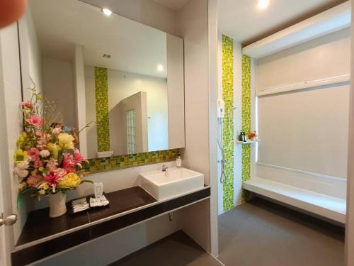 a bathroom with a sink and a mirror and a tub at Supawimol Mansion in Ban Talat Rangsit