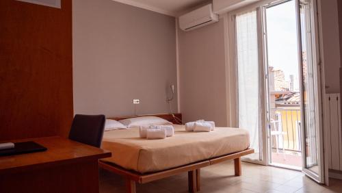 a bedroom with a bed and a desk and a window at Albergo Tecla in Lazise