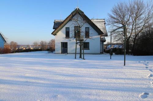 a house in the snow with footprints in front of it at Reetdachhaus im Fischerdorf in Freest