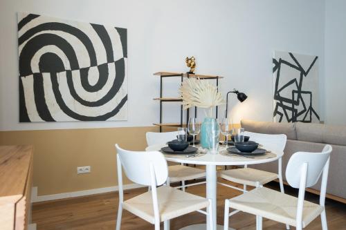 een eetkamer met een witte tafel en witte stoelen bij Contemporary 1-Bed Apartment with Balcony in the Heart of Vienna in Wenen