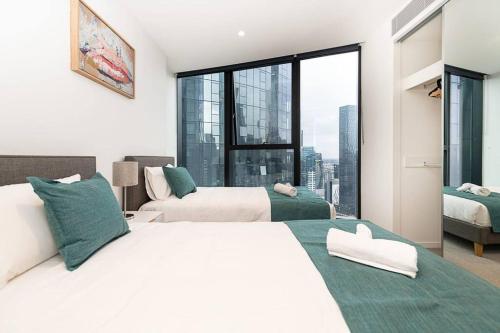een slaapkamer met 2 bedden en een groot raam bij Homely Urban Oasis in Melbourne