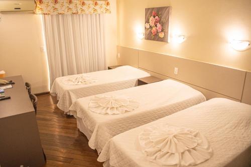 a hotel room with three beds with white sheets at Hotel Balneário in Marcelino Ramos