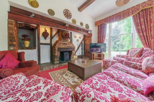 a living room with red furniture and a fireplace at Brookside Manor House in Chirk