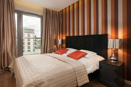 a bedroom with a large bed and a window at Apartamenty Apartinfo Waterlane in Gdańsk