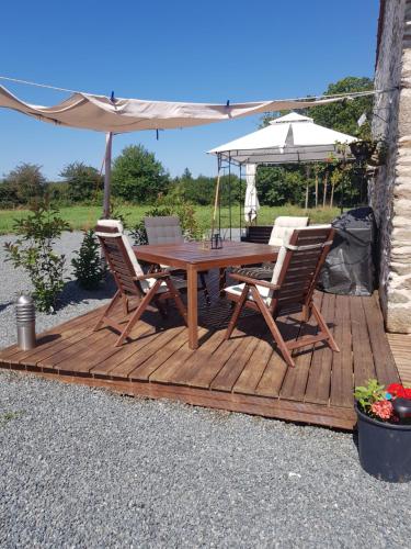 um deque de madeira com uma mesa, cadeiras e um guarda-sol em Grange Bouton d Or sleeps 2 quiet countryside location Boussac medieval town em Malleret-Boussac