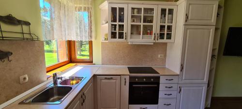 een keuken met witte kasten, een wastafel en een raam bij Mountain view in Razlog