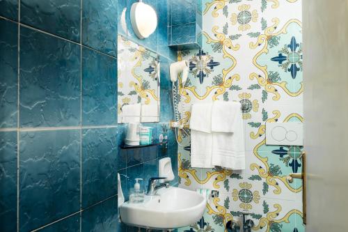 a blue bathroom with a sink and a mirror at Hotel Fontana in Amalfi