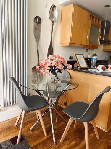 a glass table with a vase of flowers and two chairs at Canary Wharf - Luxury Apartments in London